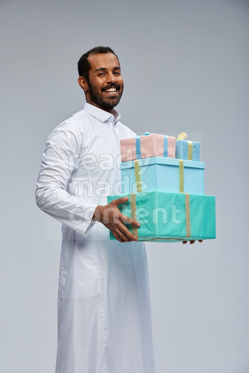 Saudi man Wearing thob standing holding gift box on Gray background