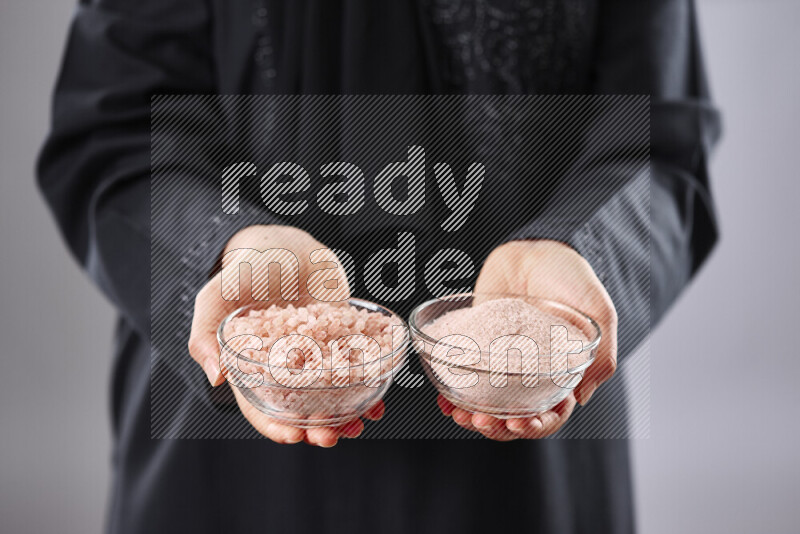 Woman in abaya holding different kinds of spices in different positions