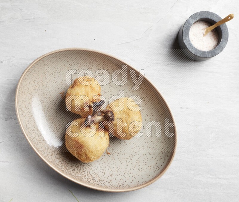 breaded drumstick on oval beige pottery plate on grey textured countertop