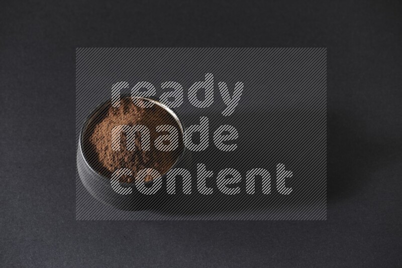 وعاء فخاري أسود ممتلئ ببودرة القرنفل علي خلفية سوداء