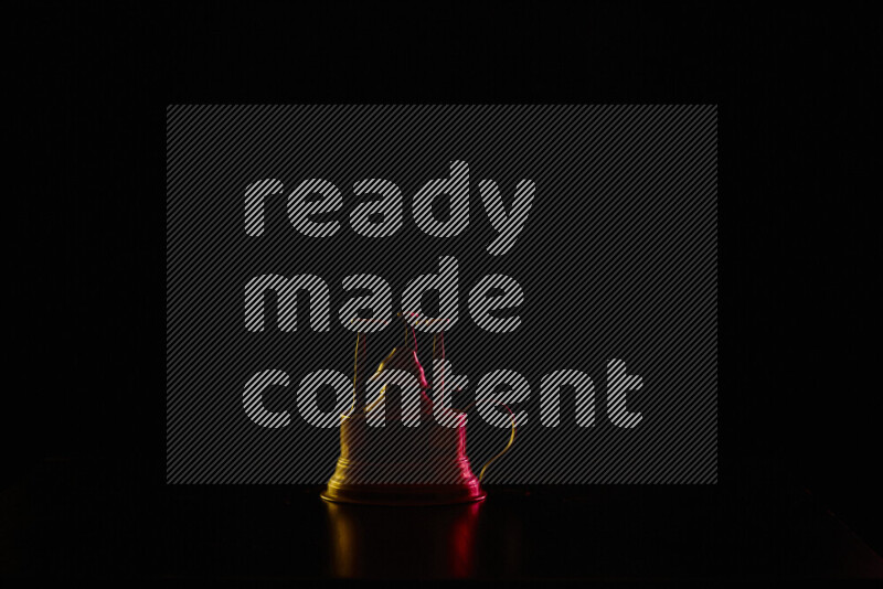 A turkish coffee maker with colored rim light against black background