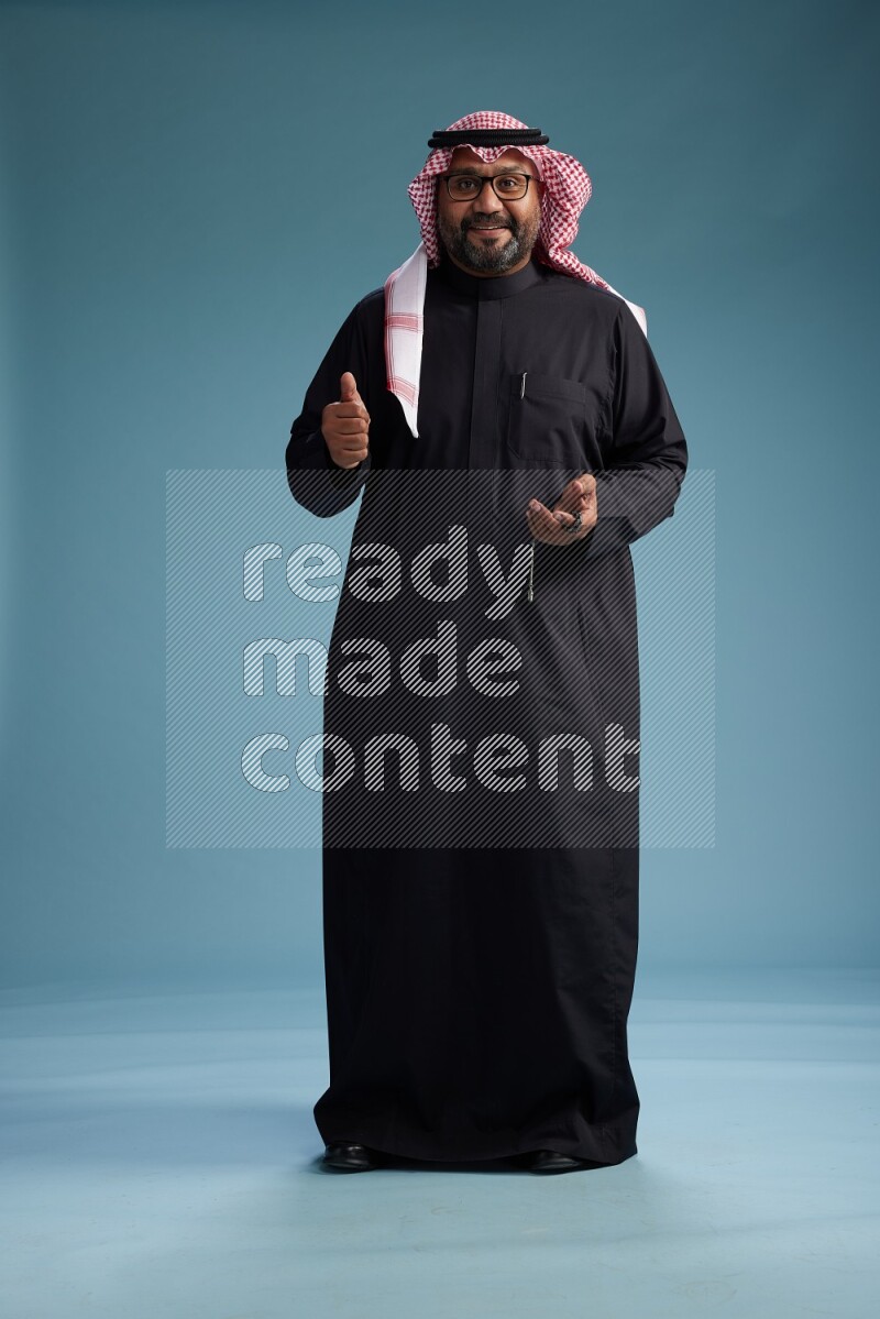 Saudi Man with shimag Standing Interacting with the camera on blue background