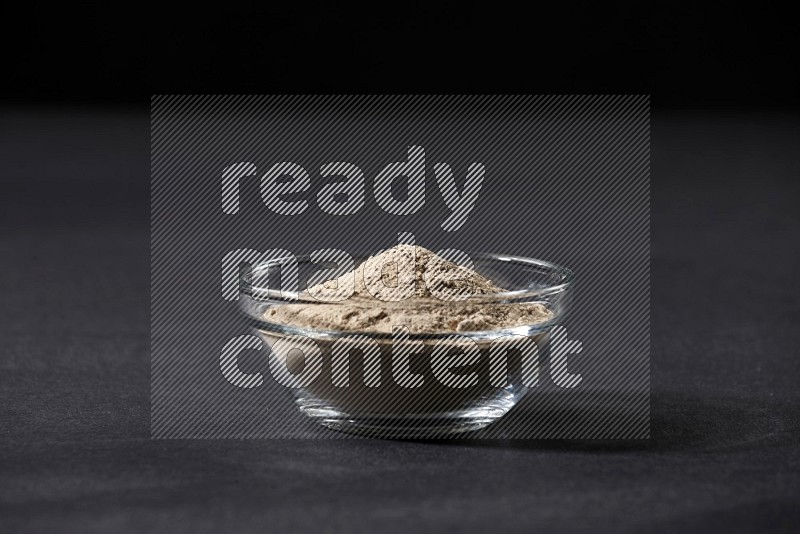 A glass bowl full of garlic powder on a black flooring in different angles