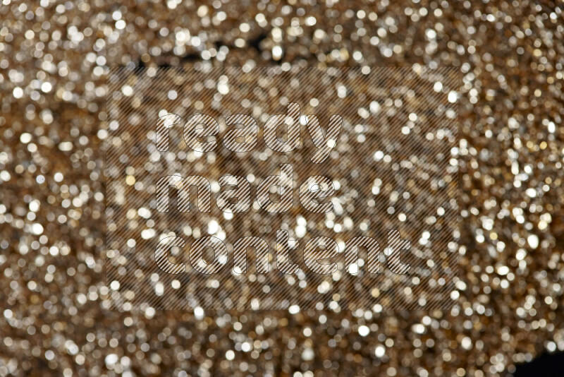 Gold shimmering fragments of glass scattered on a black background