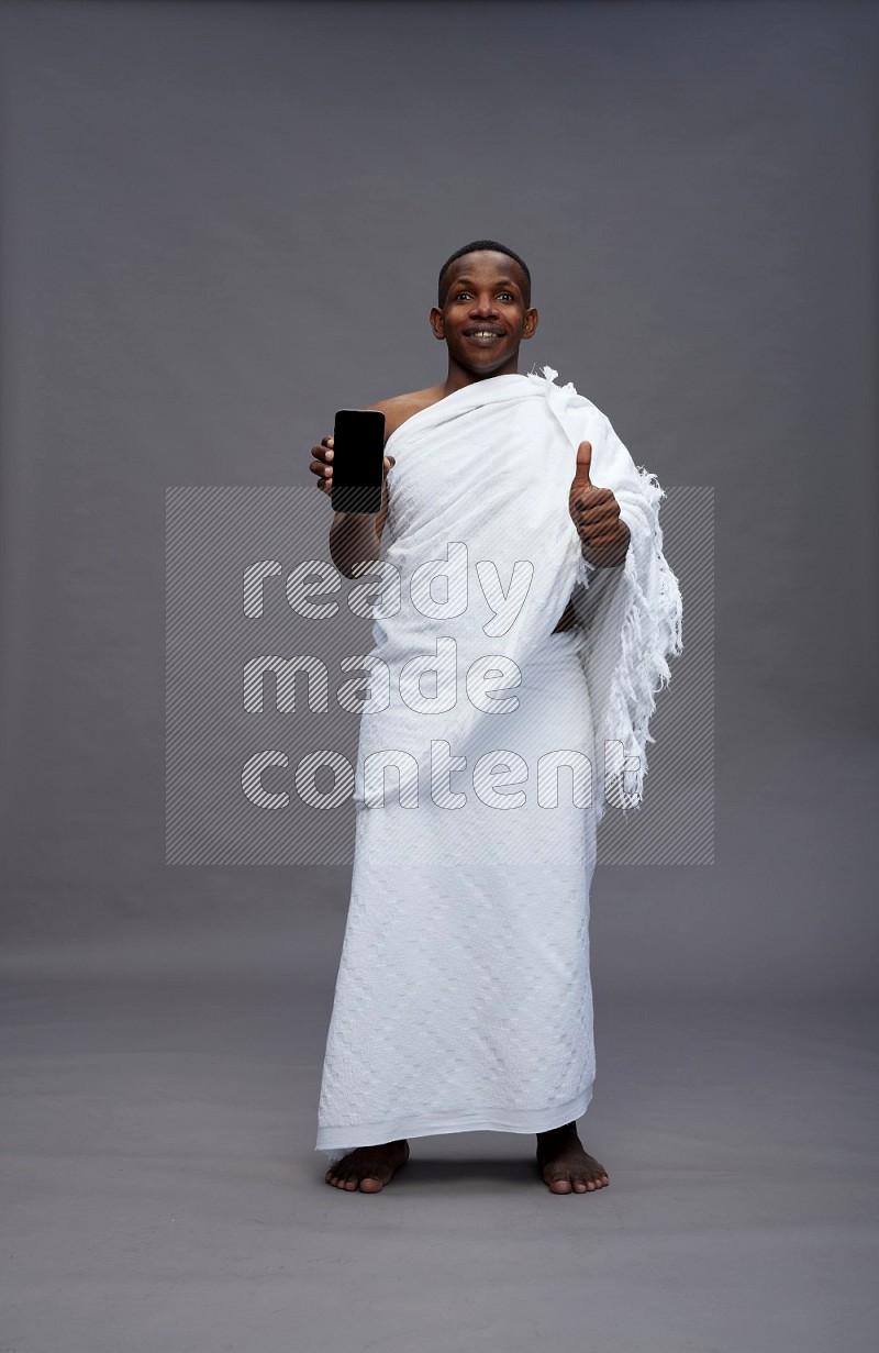 A man wearing Ehram Standing showing phone to camera on gray background