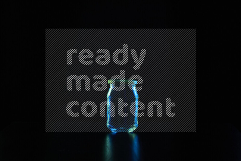 Glassware with rim light in blue and green against black background