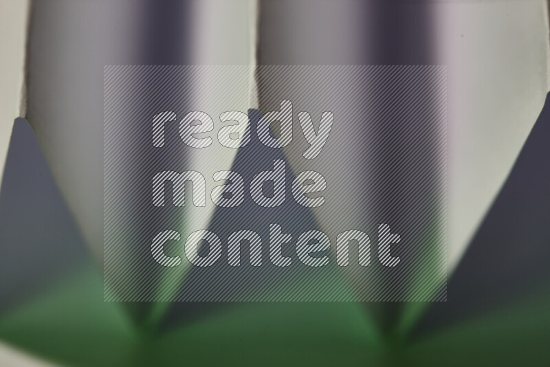 A close-up abstract image showing sharp geometric paper folds in white and green gradients