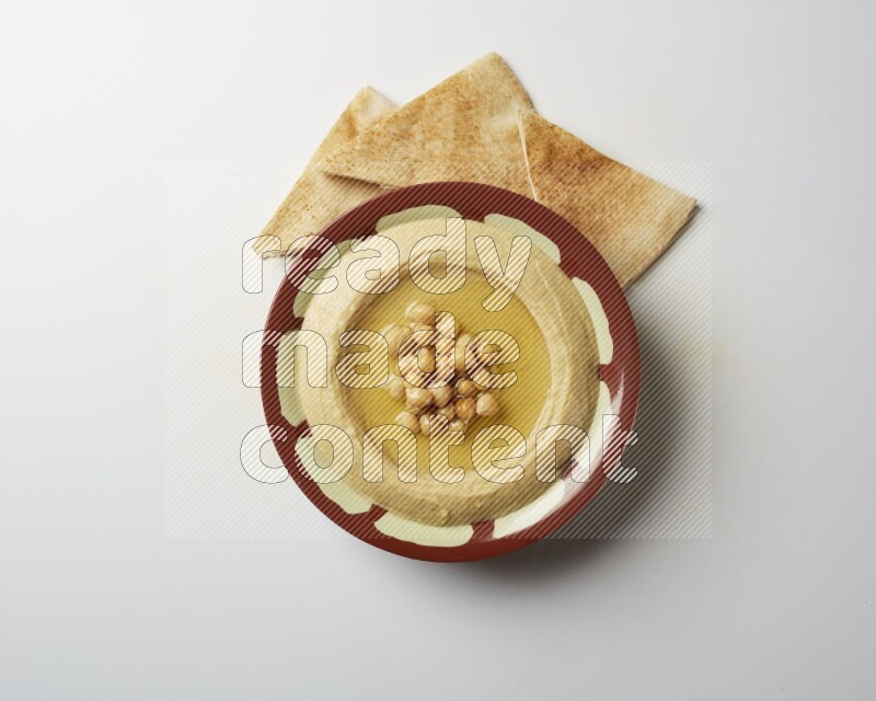 Hummus in a traditional plate garnished with roasted chickpeas  on a white background