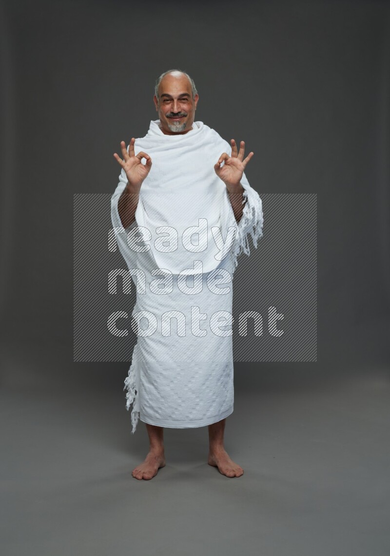 A man wearing Ehram Standing Interacting with the camera on gray background