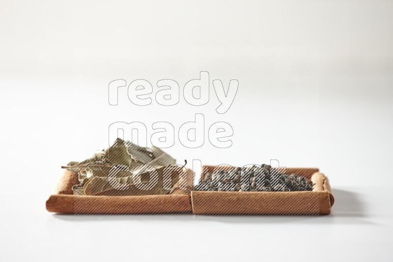 2 squares of cinnamon sticks full of black peppers and bay laurel leaves on white flooring