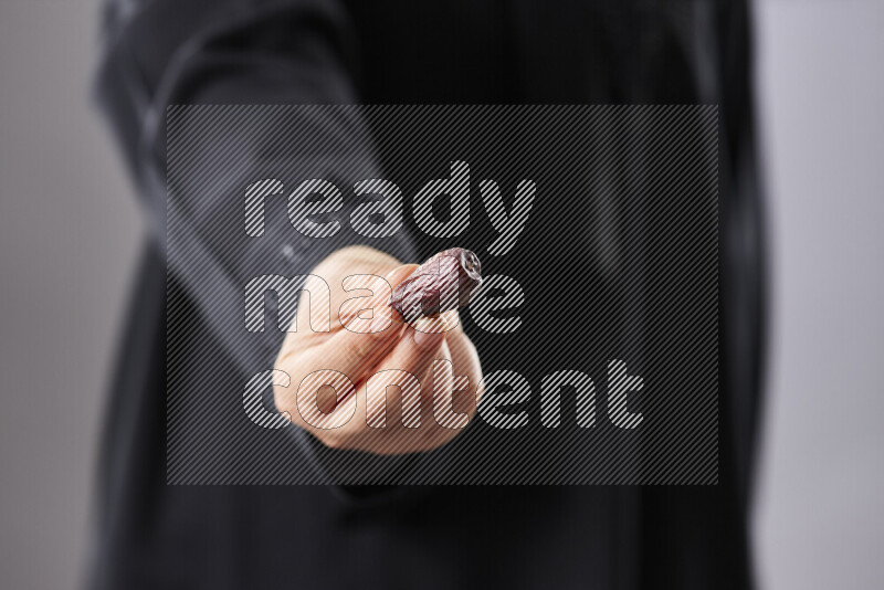Woman in abaya holding dates in different positions