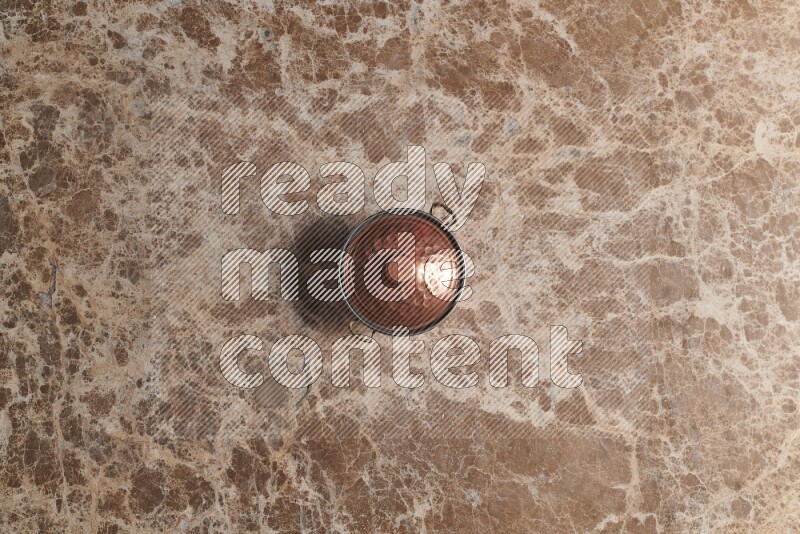 A small copper pot on beige marble background