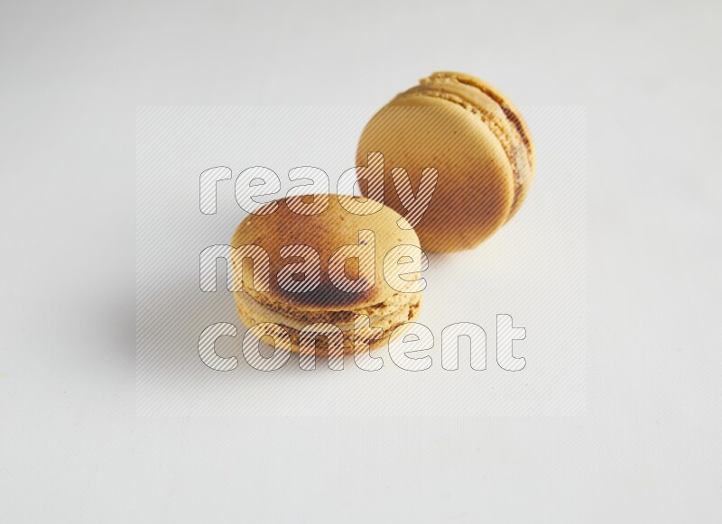 45º Shot of two Yellow Crème Brulée macarons on white background