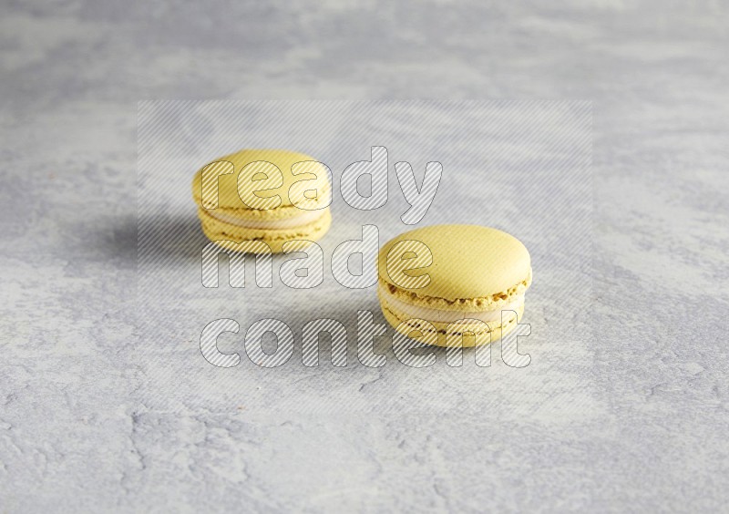 45º Shot of two Yellow Lime macarons  on white  marble background