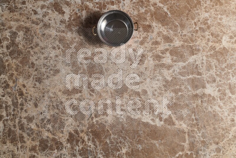 A small copper pot on beige marble background