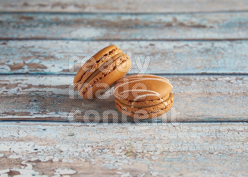 45º Shot of of two assorted Brown Irish Cream, and Brown Maple Taffy macarons  on light blue background