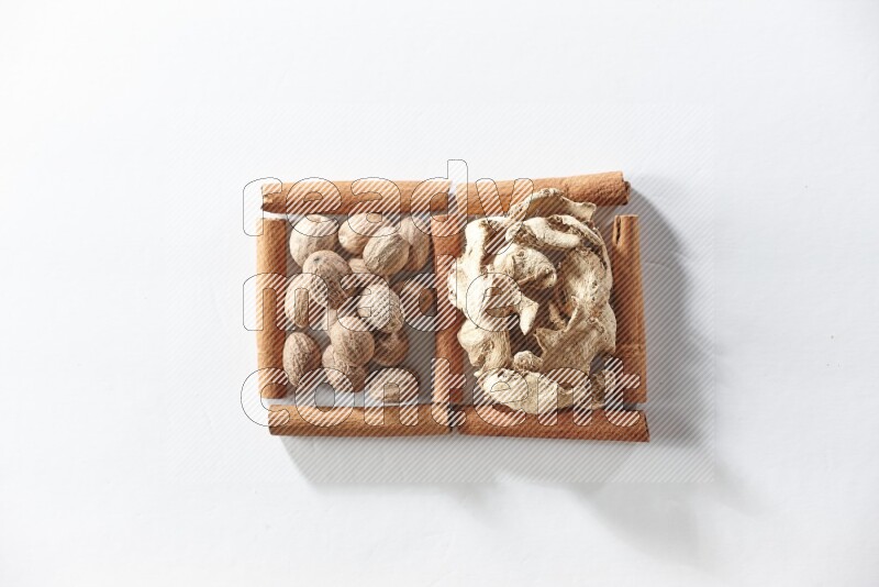 2 squares of cinnamon sticks full of dried ginger and nutmegs on white flooring