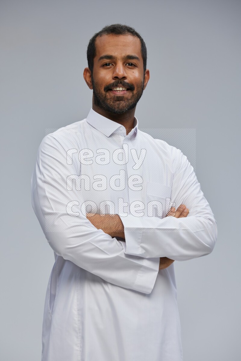Saudi man wearing Thob standing with crossed arms on Gray background