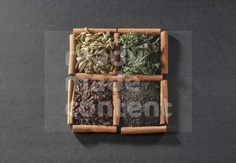 4 squares of cinnamon sticks full of black tea, cloves, dried mint leaves and cardamom on black flooring