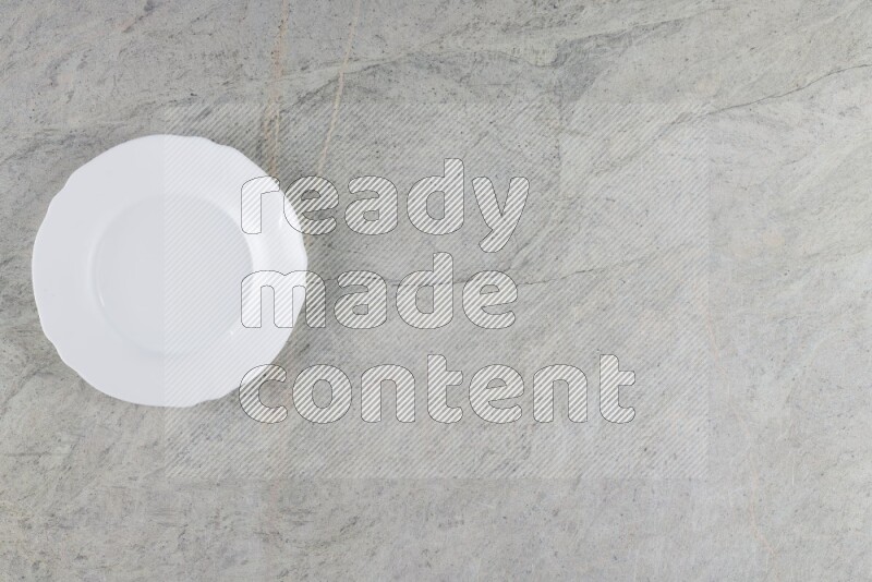 A white ceramic circular plate on grey marble background