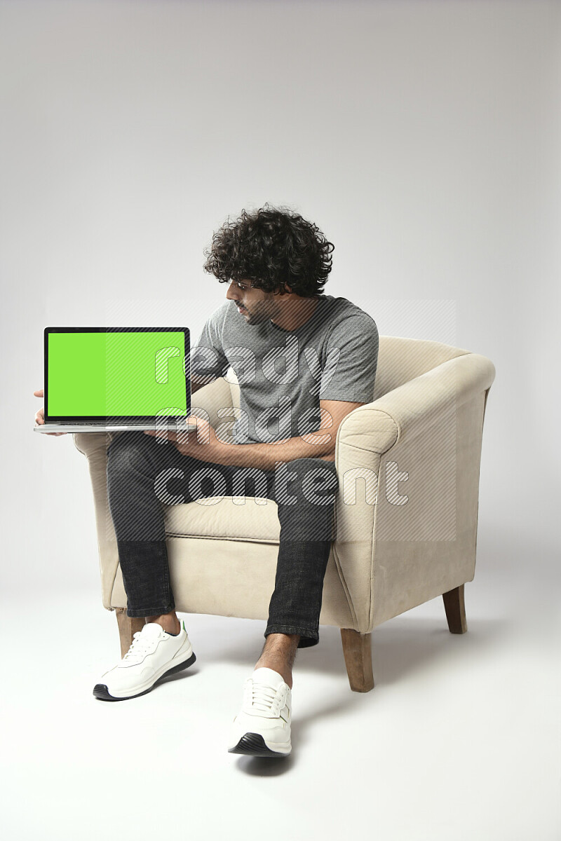 A man wearing casual sitting on a chair showing a laptop screen on white background