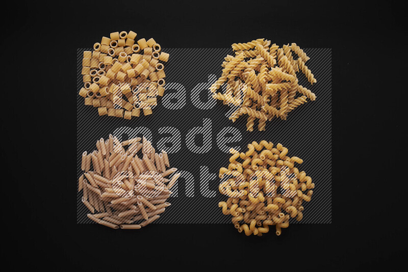 Different pasta types in bunches on black background