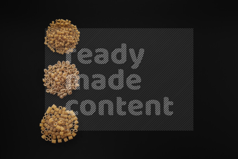 Different pasta types in 3 bunches on black background