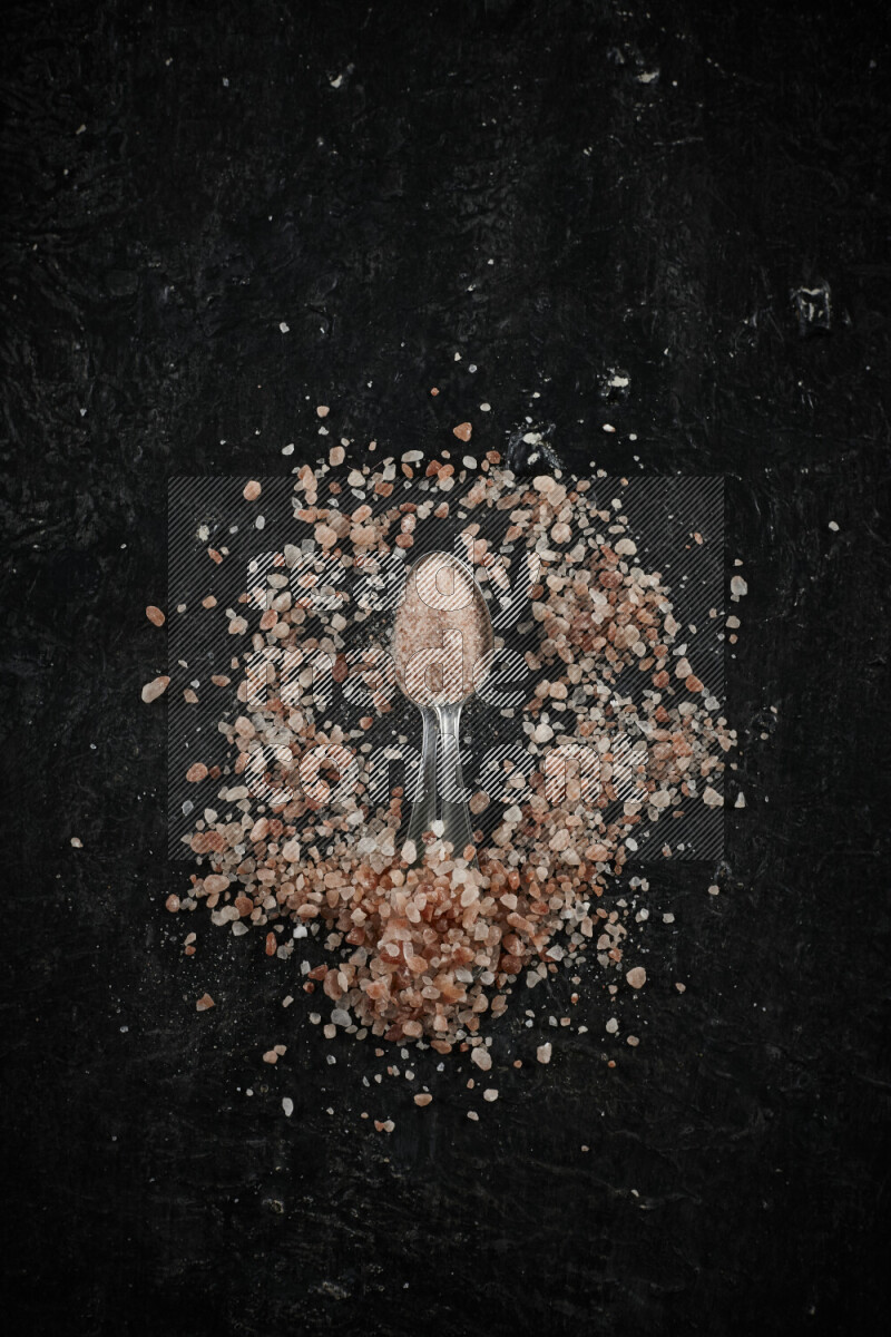 ملعقتان معدنيتان ممتلئتان بملح الهيمالايا الوردي على خلفية سوداء