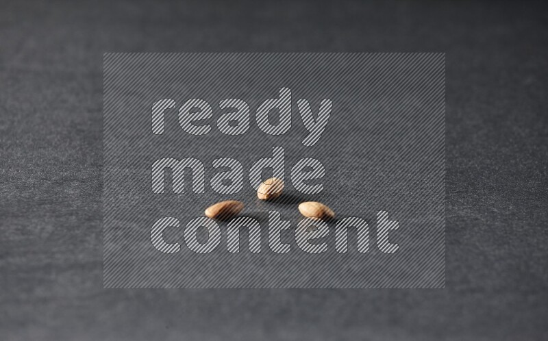 3 peeled almonds on a black background in different angles