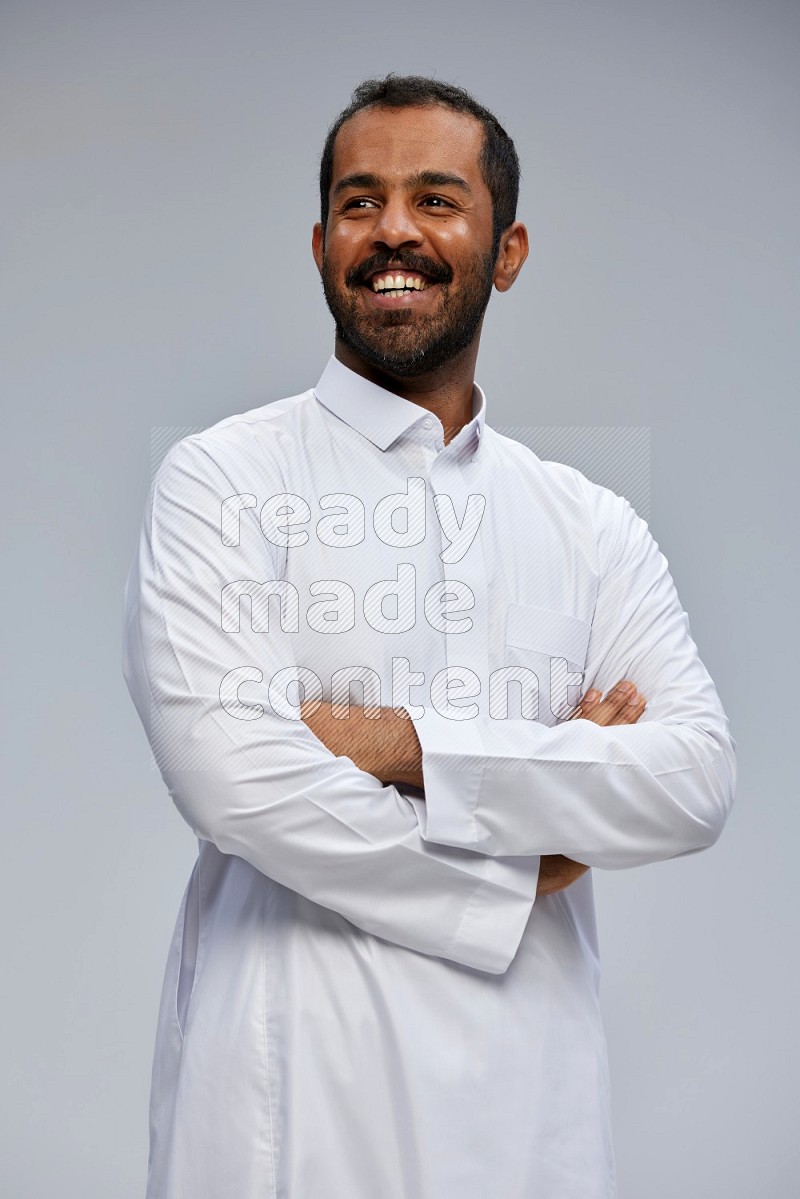 Saudi man wearing Thob standing with crossed arms on Gray background