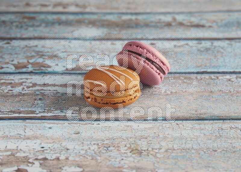 45º Shot of of two assorted Brown Irish Cream, and Purple Strawberry macarons  on light blue background