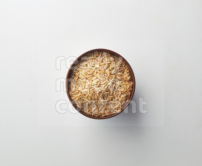 Top-view shot of long grain brown rice in a container on white background