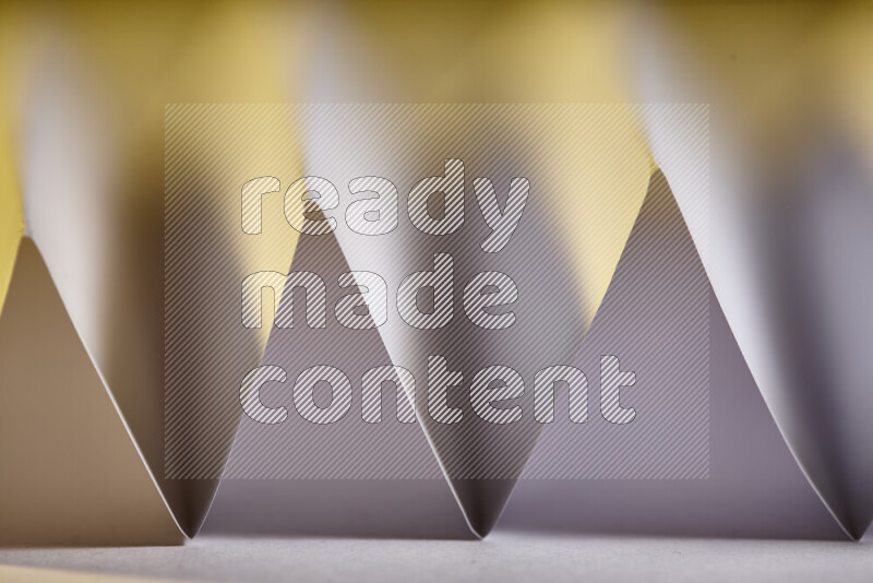 صورة مجردة مقربة تظهر طيات ورقية هندسية حادة بتدرجات اللون الأبيض مع درجات لونية دافئة