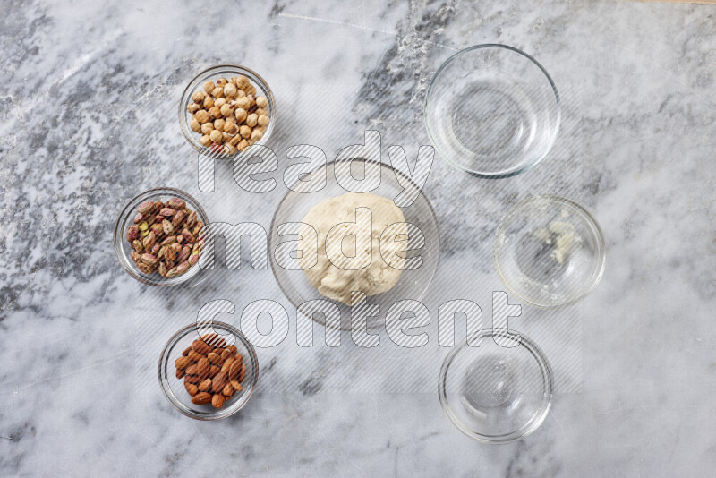 Ghoriba step by step with its ingredient, flour, powdered sugar, ghee and nuts on grey marble background