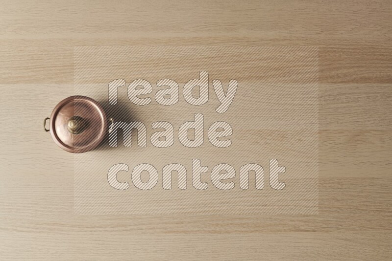 وعاء نحاسي صغير على خلفية خشبية فاتحة