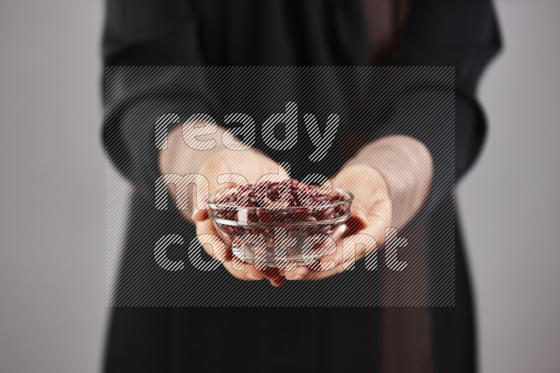 Woman in abaya holding different kinds of legumes in different positions