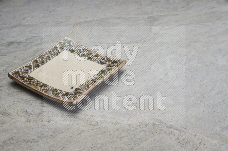 A decorative pottery plate on grey marble background