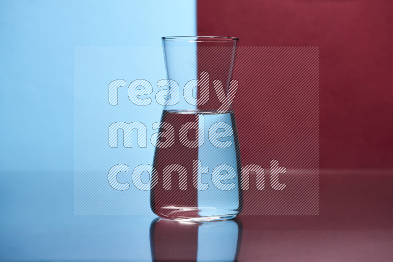 The image features a clear glassware filled with water, set against light blue and dark red background