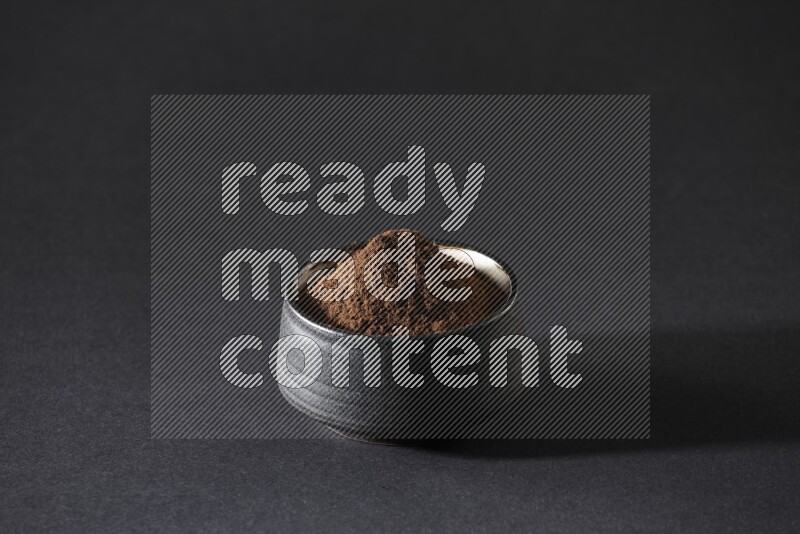 وعاء فخاري أسود ممتلئ ببودرة القرنفل علي خلفية سوداء