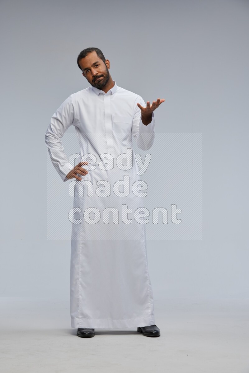 Saudi man Wearing Thob standing interacting with the camera on Gray background