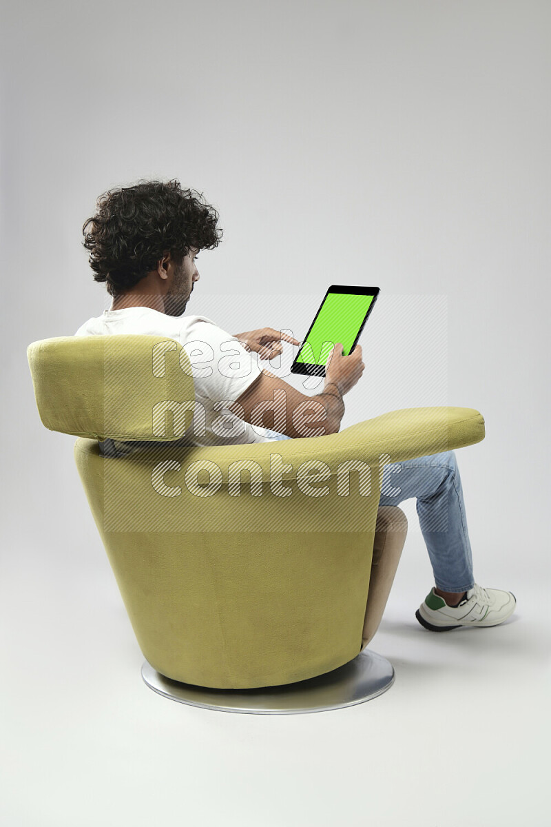 A man wearing casual sitting on a chair showing a tablet screen on white background