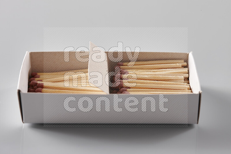 An open matchbox revealing wooden matches on a grey background