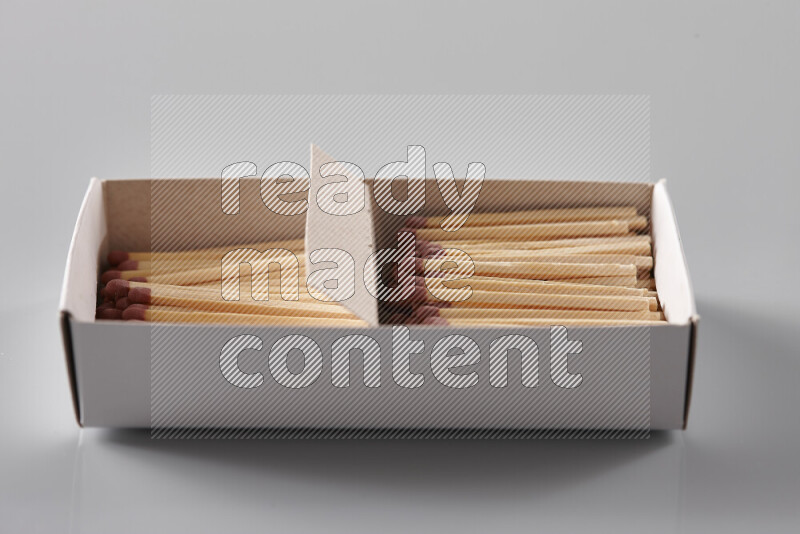 علبة كبريت مفتوحة تكشف عن أعواد ثقاب خشبية على خلفية رمادية