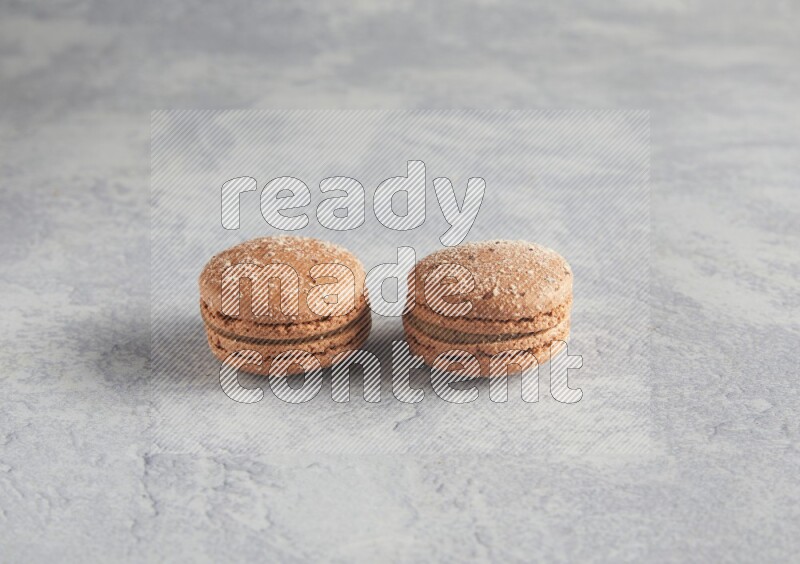 45º Shot of two Brown Hazelnuts macarons  on white  marble background