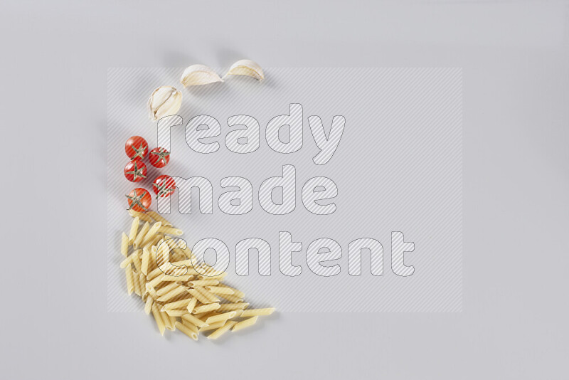 Mini penne with garlic, cherry tomatoes and wheat stalks on light grey background