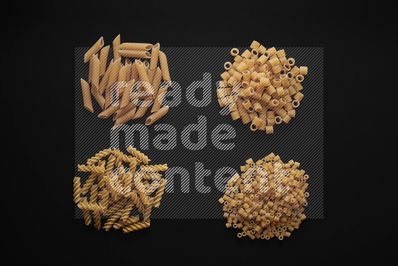 Different pasta types in bunches on black background