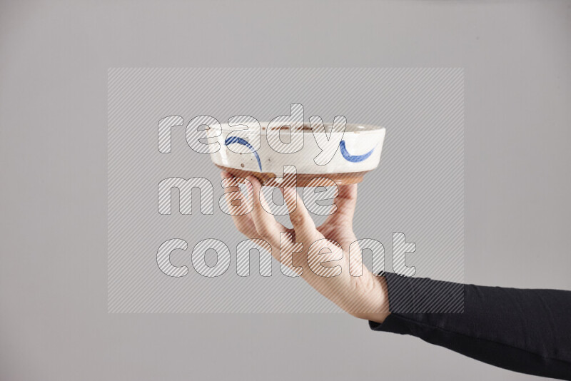 A woman in black abaya holding different pottery essentials in different positions