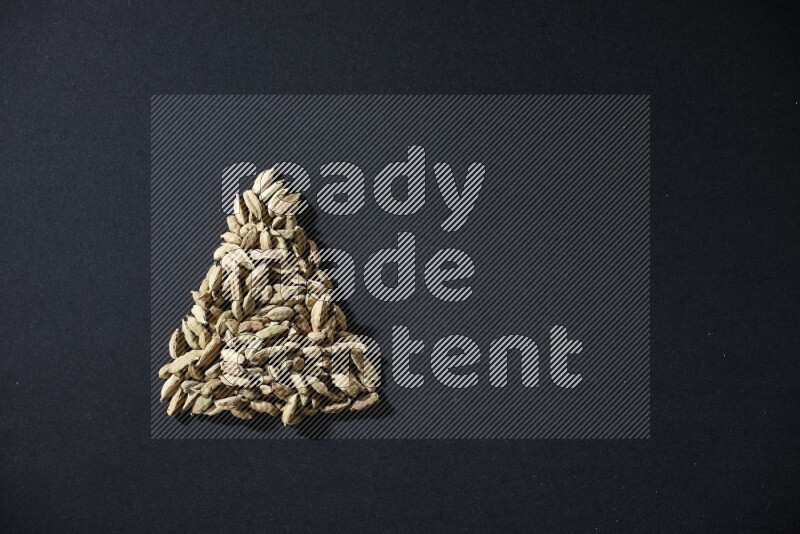 Cardamom in a triangle shape on black flooring