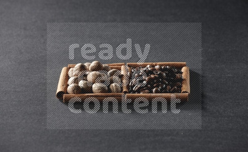 مربعان من أعواد القرفة ممتلئان بحبوب القهوة وجوزة الطيب علي خلفية سوداء