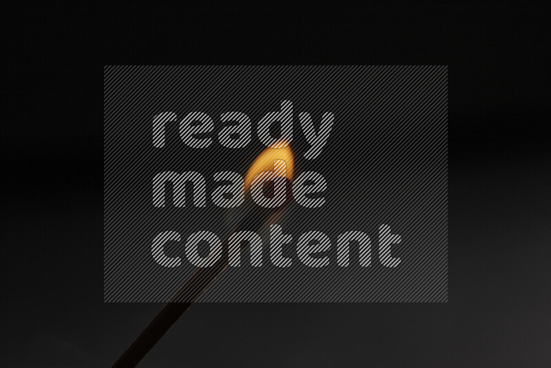 A burning matchstick isolated on dark backdrop